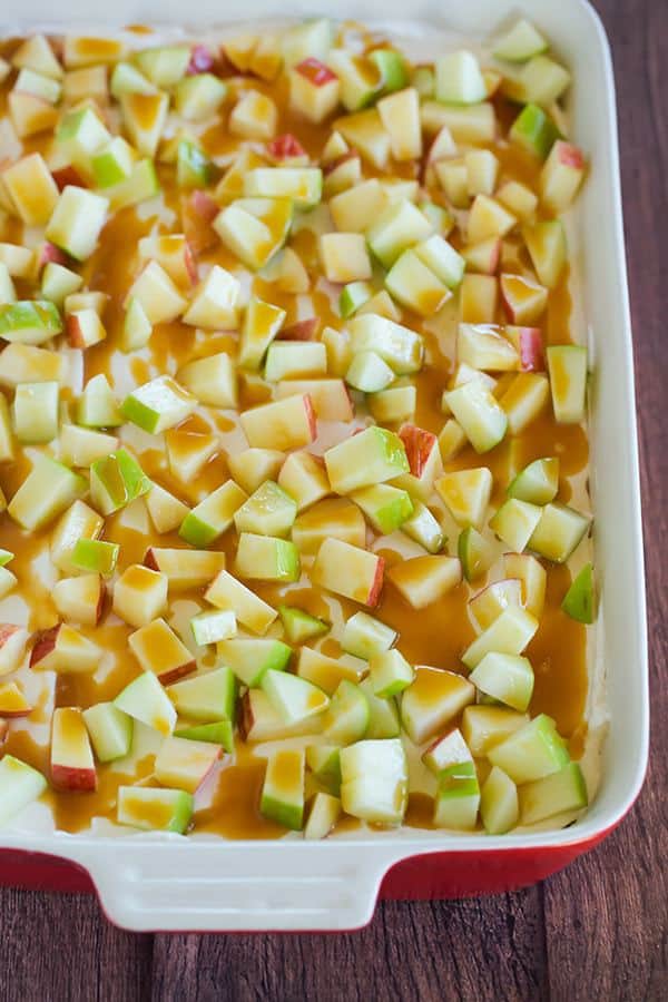 This caramel apple pudding has layers of caramel cheesecake filling, caramel pudding, a whipped cream topping, apples, and peanuts all on top of a gingersnap crust.