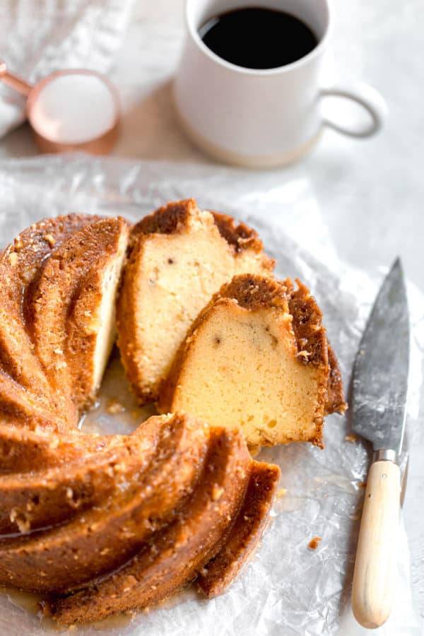 Sliced rum cake with a serving knife and cup of coffee.