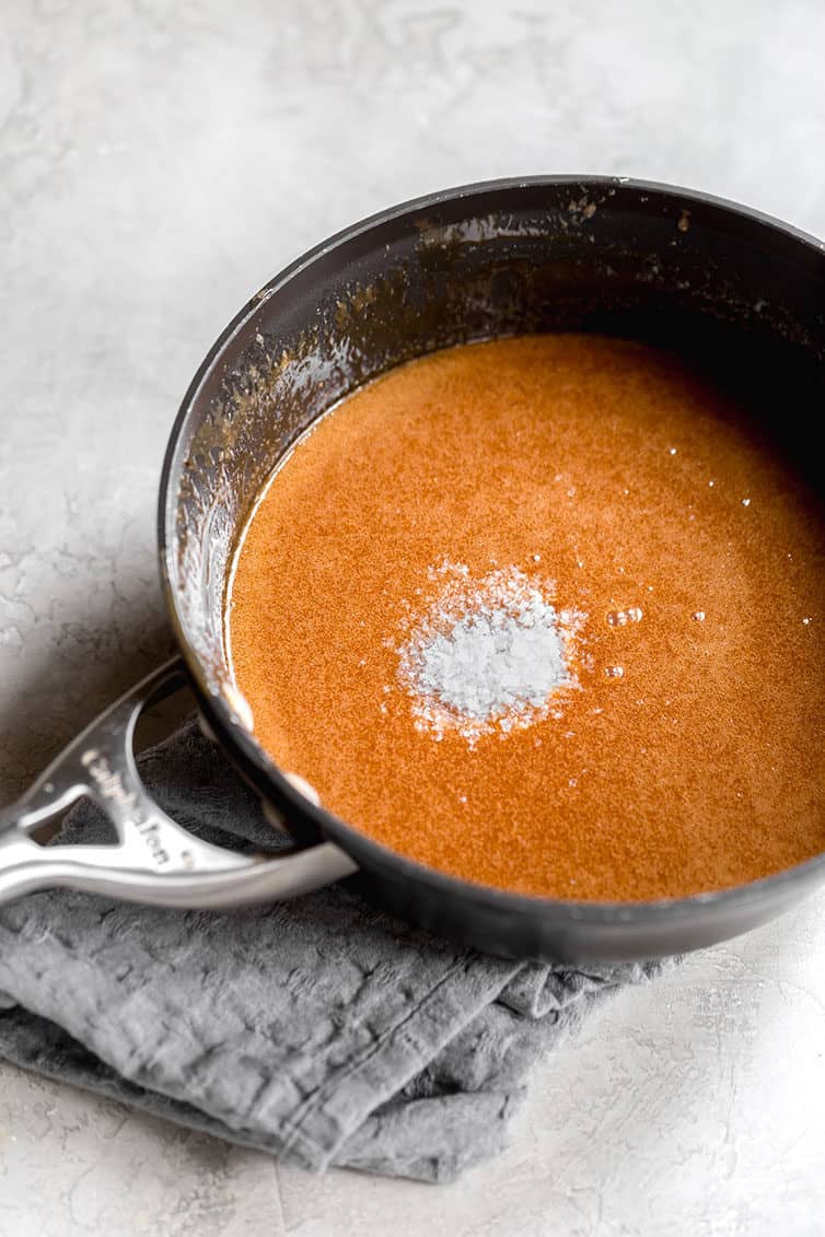 a pot filled with homemade caramel sauce that is topped with flakey sea salt