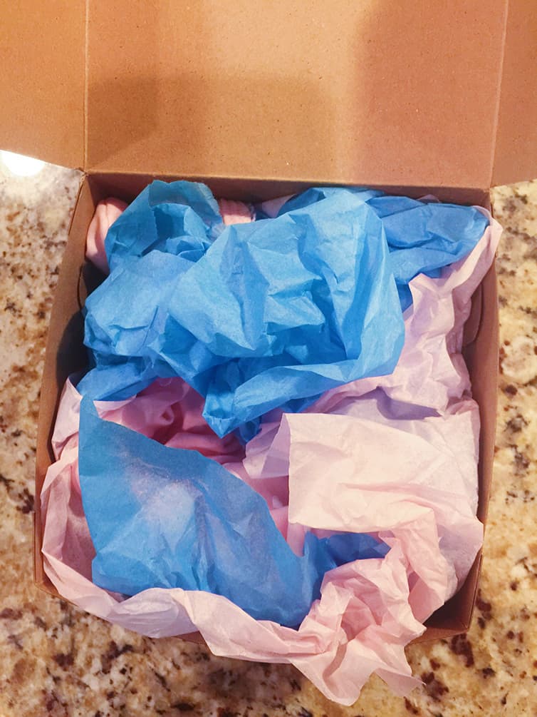 A box with blue and pink tissue paper for gender reveal.
