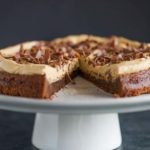 Brownie Cake with Cookie Butter Frosting on a serving platter with a slice missing.