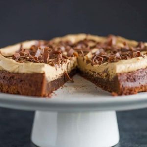 Brownie Cake with Cookie Butter Frosting on a serving platter with a slice missing.