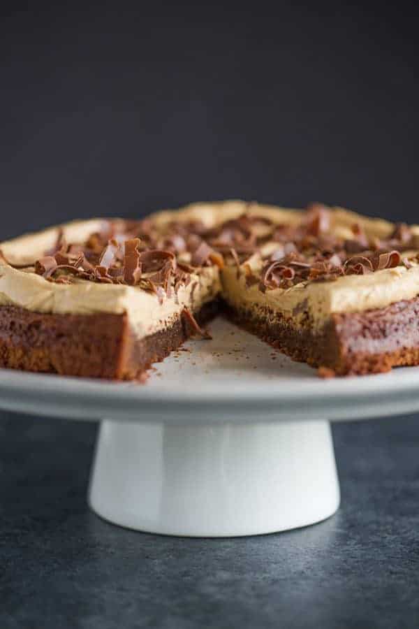 Brownie Cake with Cookie Butter Frosting on a serving platter with a slice missing.
