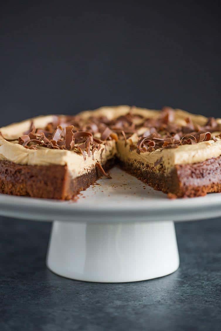 Brownie Cake with Cookie Butter Frosting on a serving platter with a slice missing.