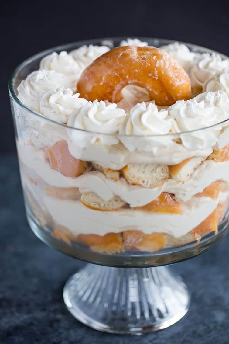 Layers of chopped doughnuts and coffee whipped cream in a trifle bowl.