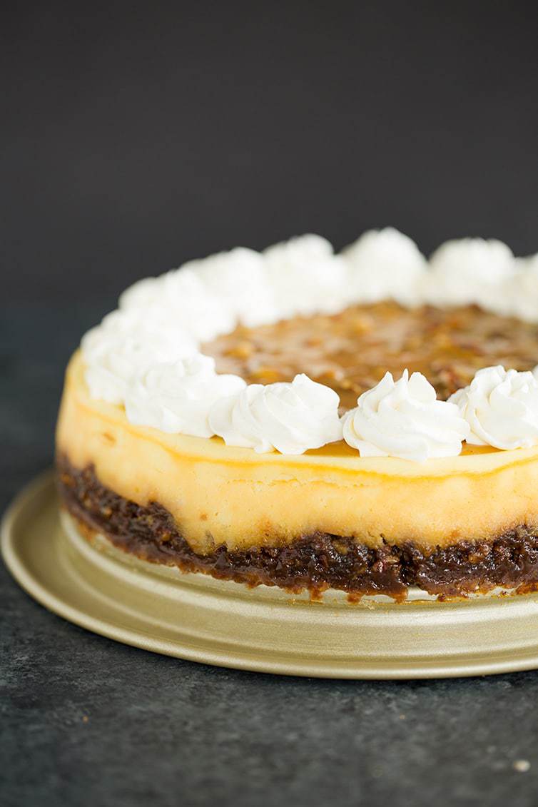 A pecan pie cheesecake with whipped cream rosettes on top.