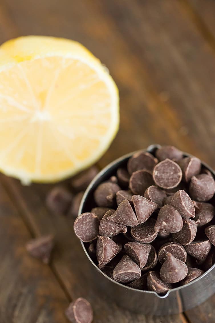 A sliced lemon and measuring cup with chocolate chips.