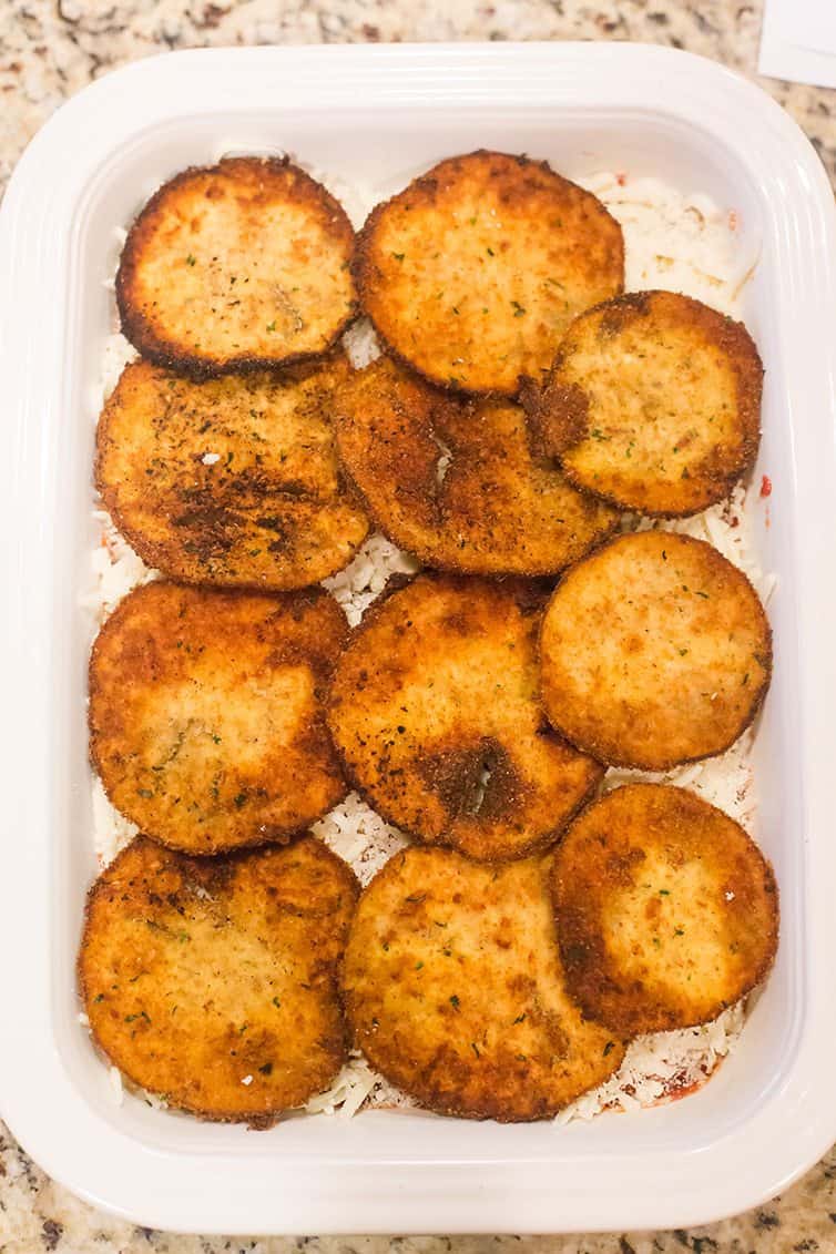 Eggplant slices being assembled into eggplant parmesan.