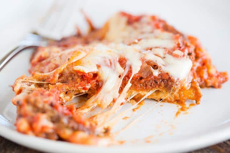 A slice of eggplant parmesan cut with melted cheese.