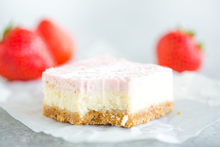 A strawberry cheesecake bar with a bite taken out of it.