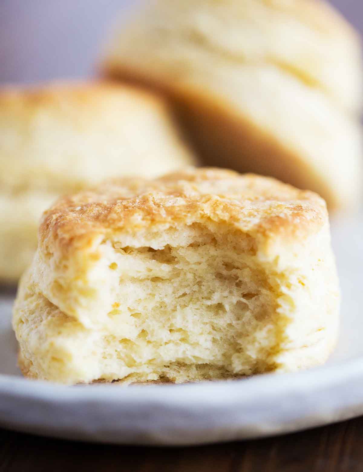 Homemade buttermilk biscuit with a bite taken out, showcasing how many flaky layers are inside.