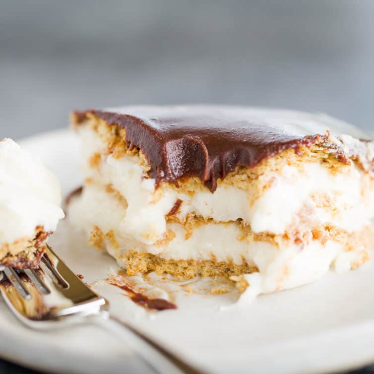 A piece of chocolate eclair cake with a forkful taken out of it.
