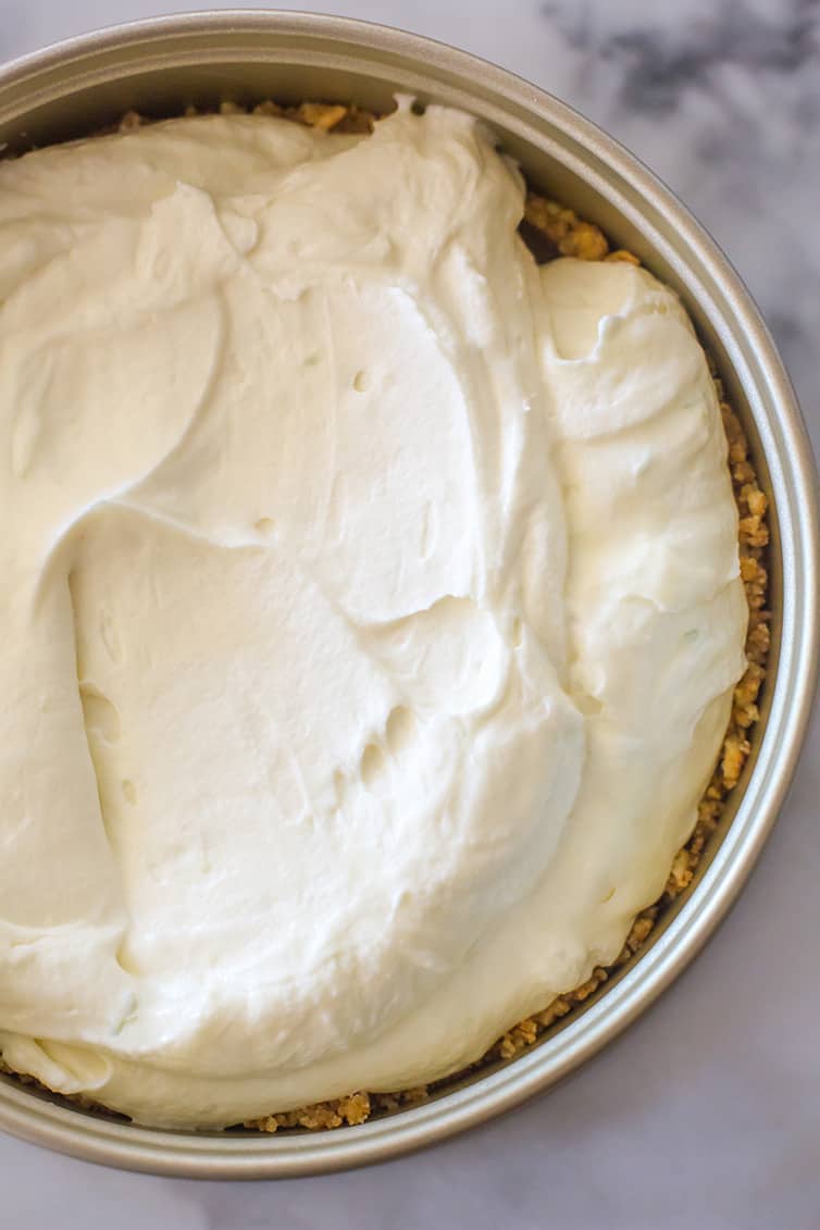 Key lime cheesecake filling spread in a springform pan.