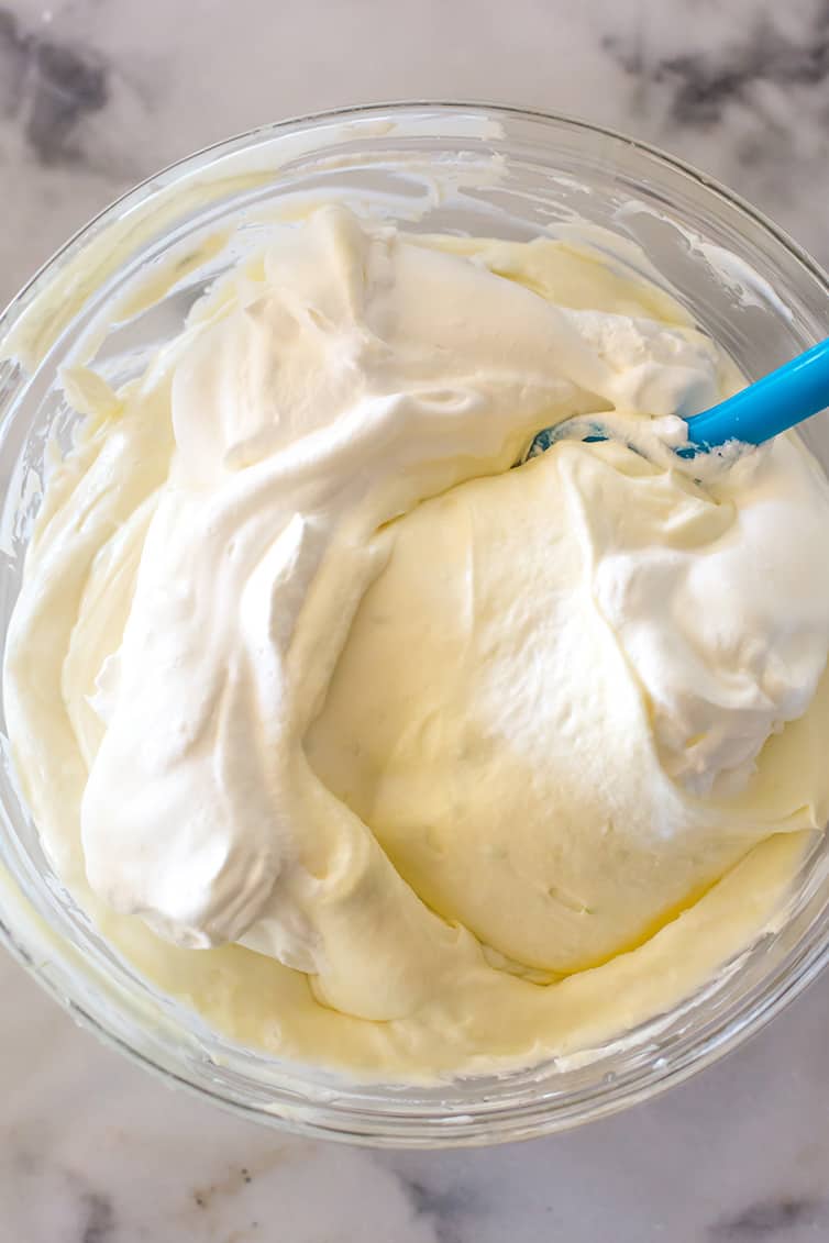 Folding heavy cream into the key lime cheesecake mixture.