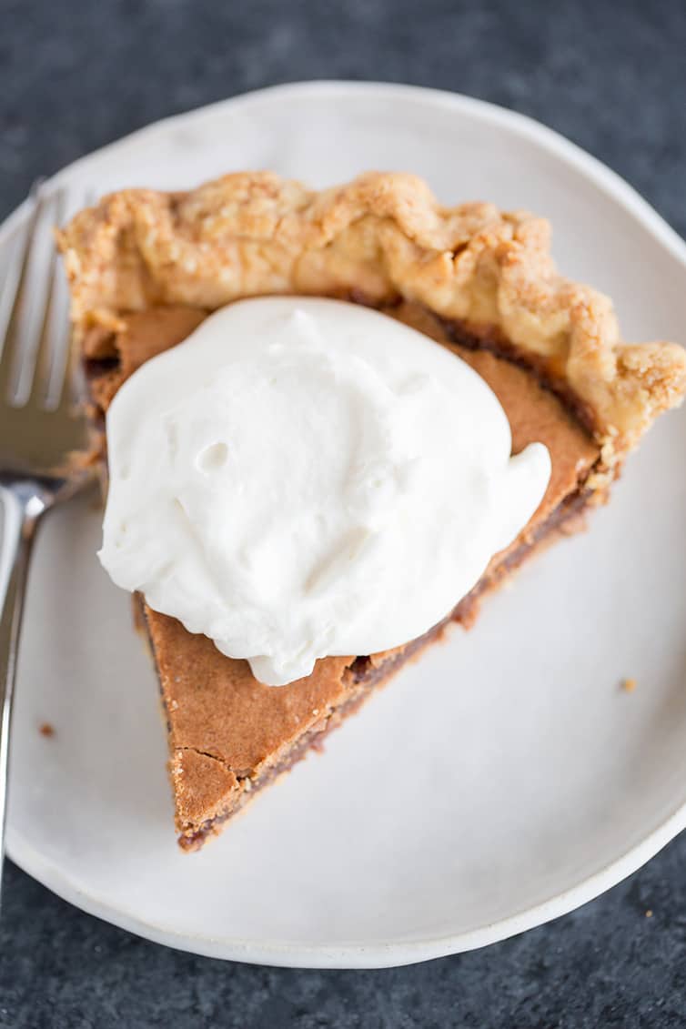 A slice of chocolate chess pie with whipped cream on top.