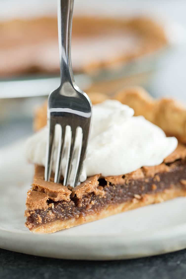 A slice of chocolate chess pie with a fork going through it.