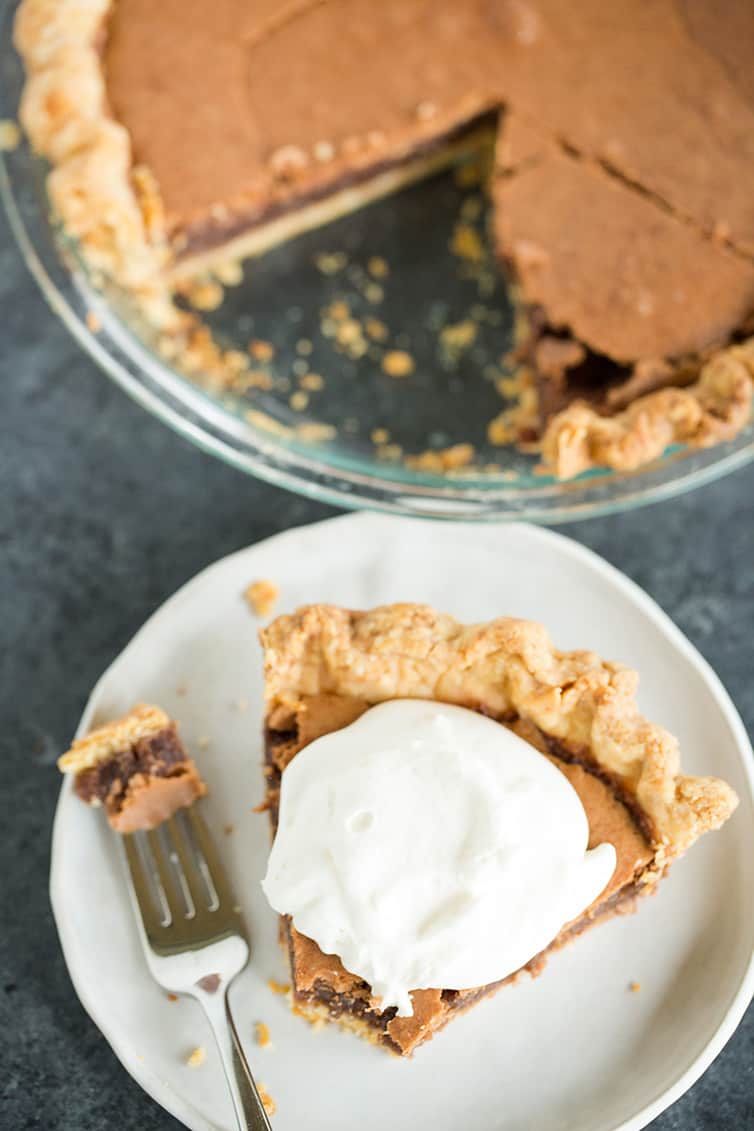 An overhead shot of a piece of chocolate chess pie and pie plate with the slice removed.