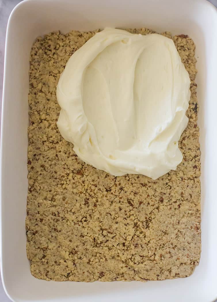 A cream cheese layer being spread over the crust.