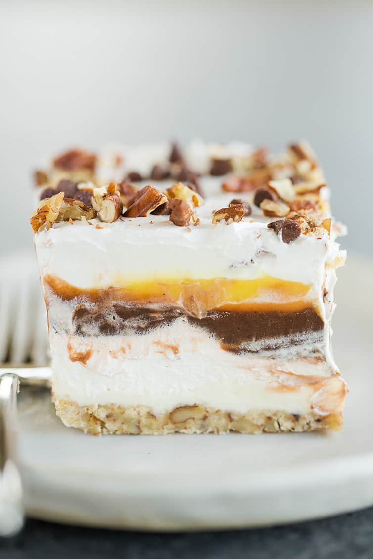 A piece of chocolate lush dessert on a plate with a fork.