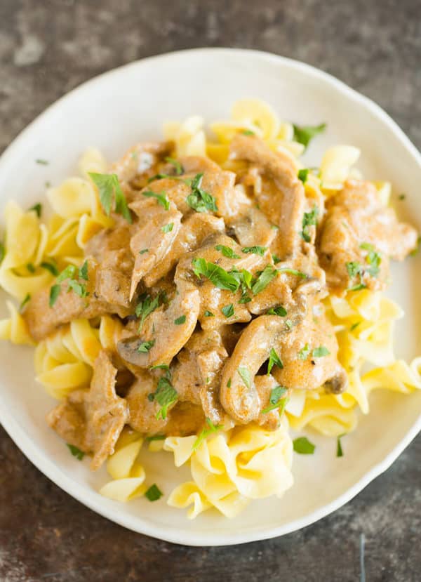 A plate of beef stroganoff over egg noodles.