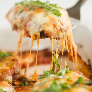 A piece of chicken parmesan being lifted out of the pan.