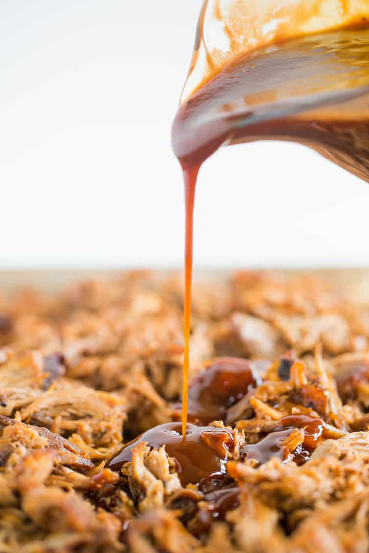 Pouring homemade bbq sauce on pulled pork.