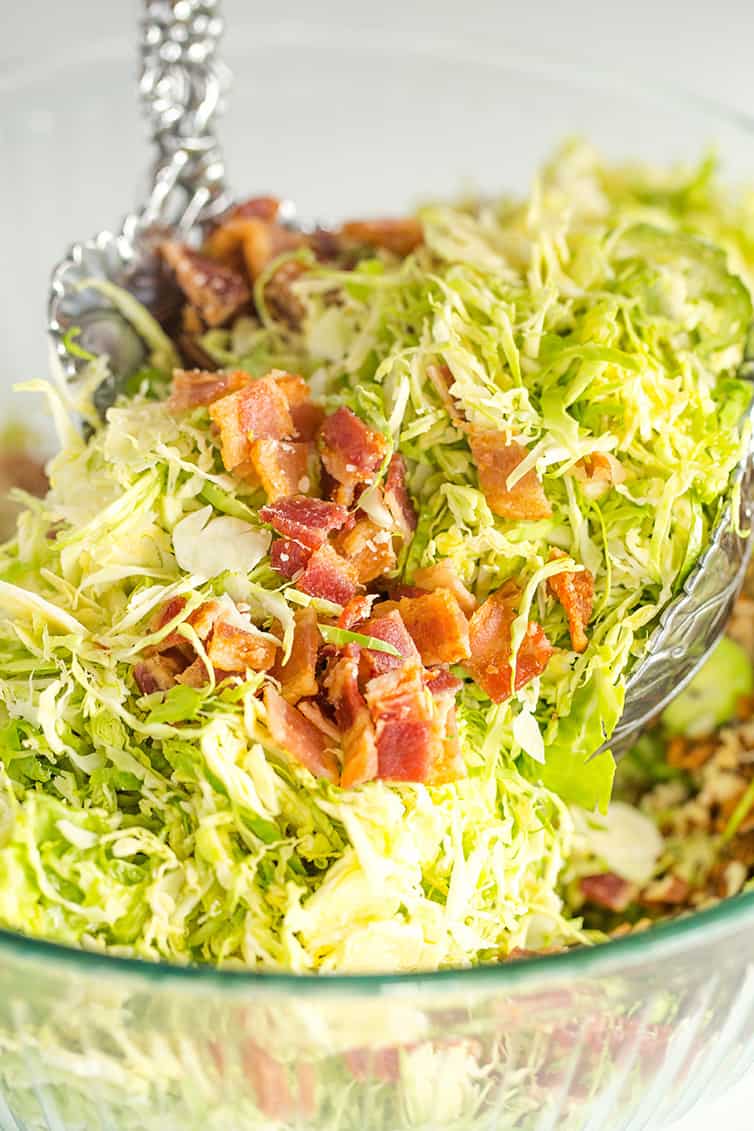 Tossing brussels sprouts salad with bacon, pecans and Parmesan cheese.