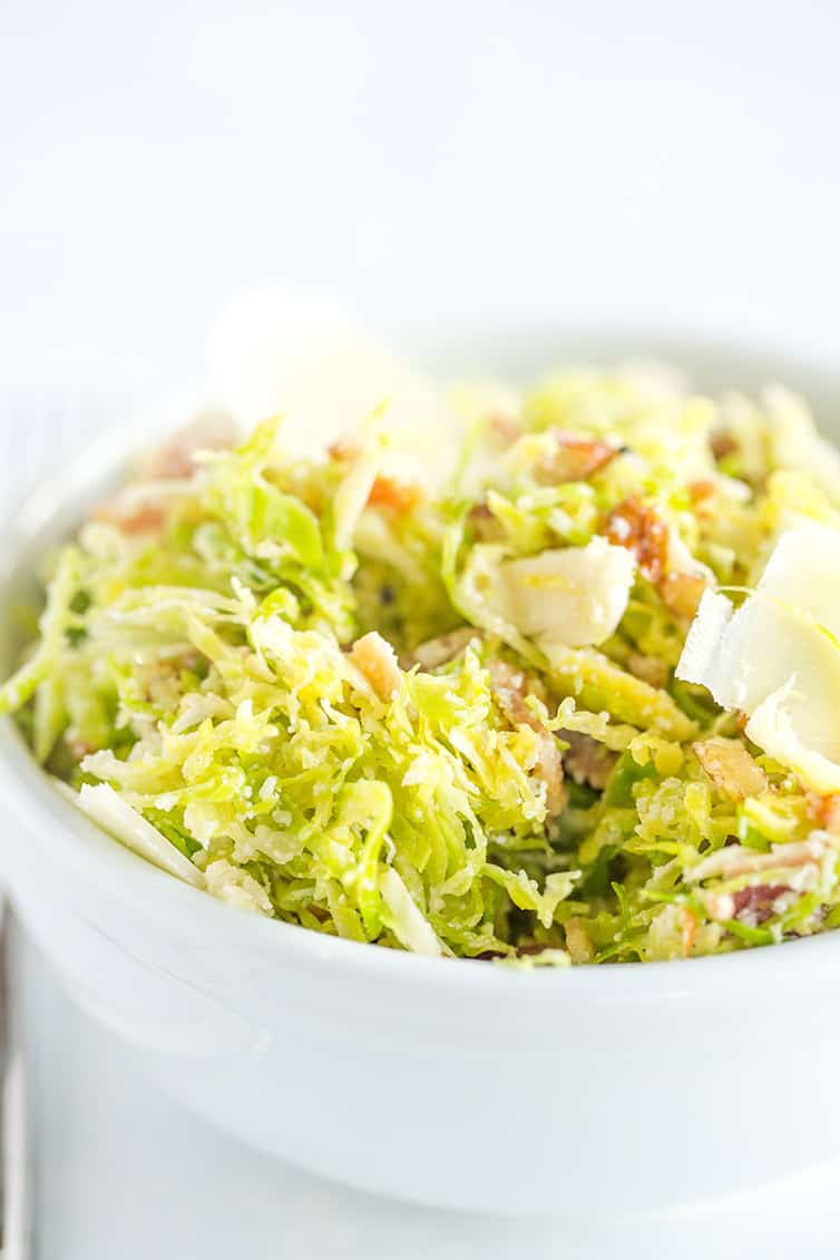 A bowl of Brussels sprouts salad with bacon, pecans and Parmesan cheese.