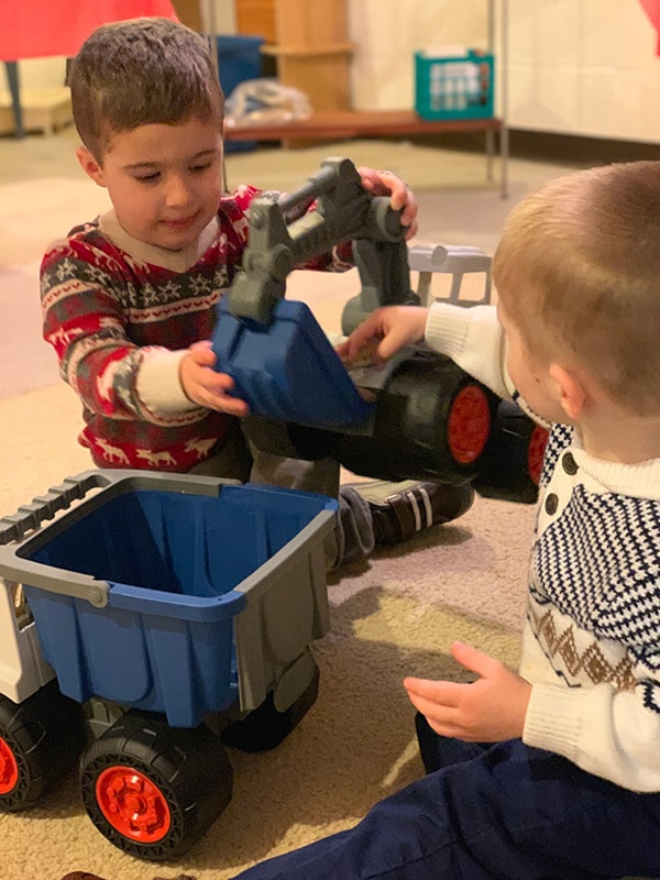 Boys playing with toy trucks on the floor.