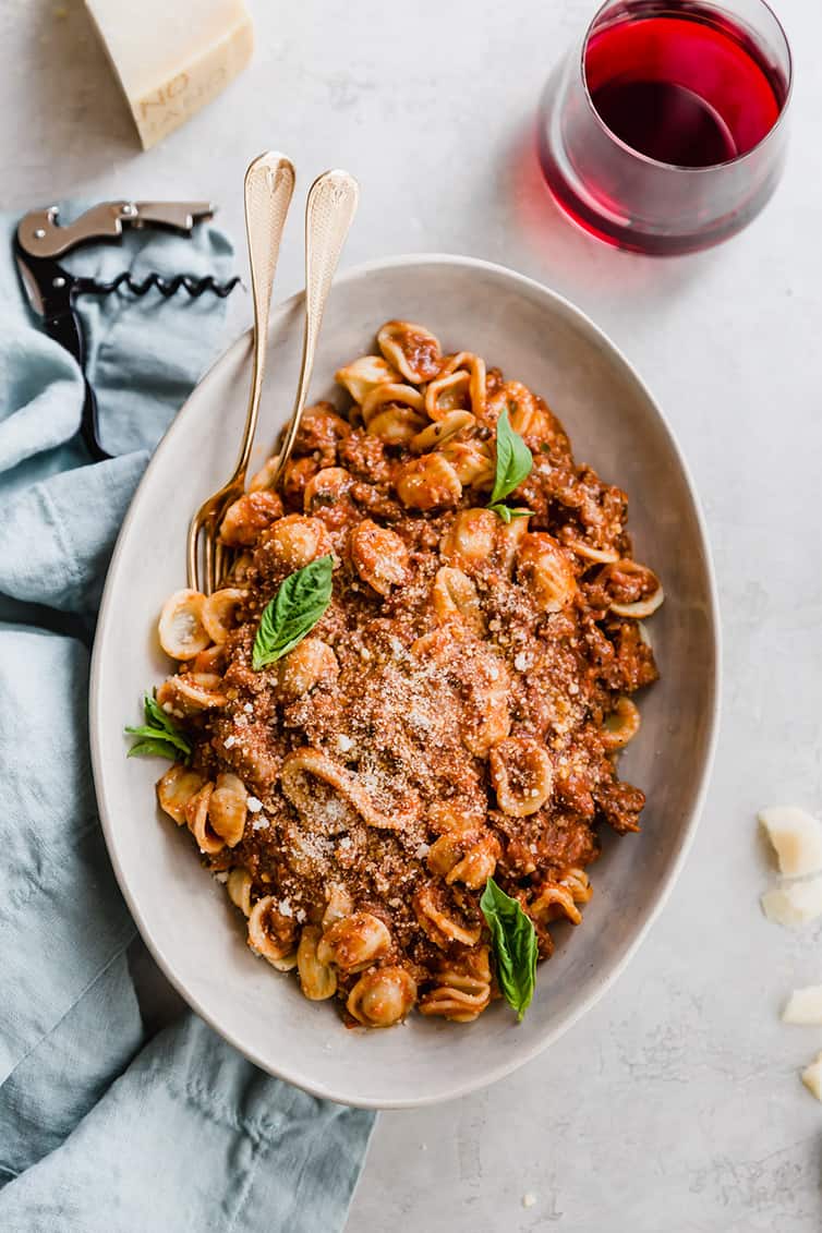 An overhead photo of a serving dish with pasta and bolognese sauce.