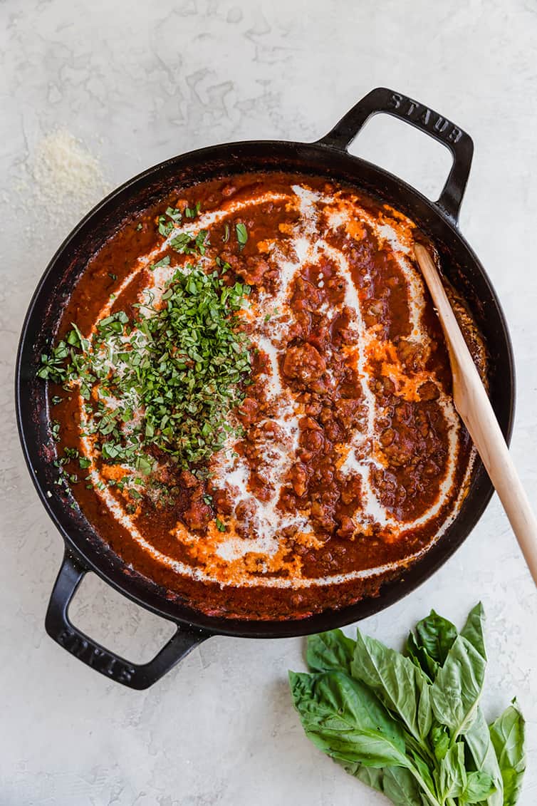 A pan of bolognese sauce with cream and fresh basil added.