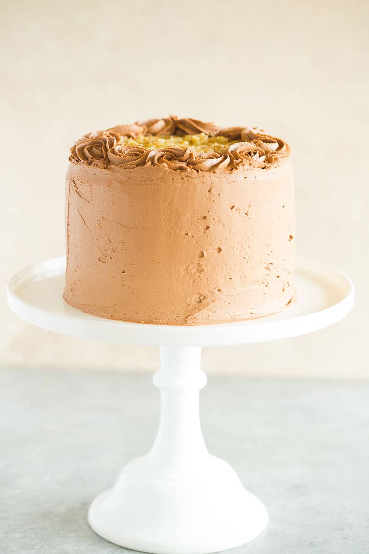 A straight-on photo of chocolate cake on a white cake platter.
