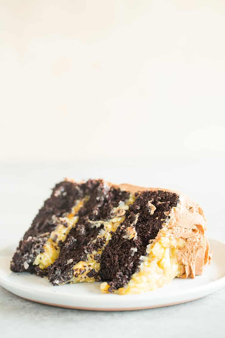 A slice of German chocolate cake on its side on a white plate.