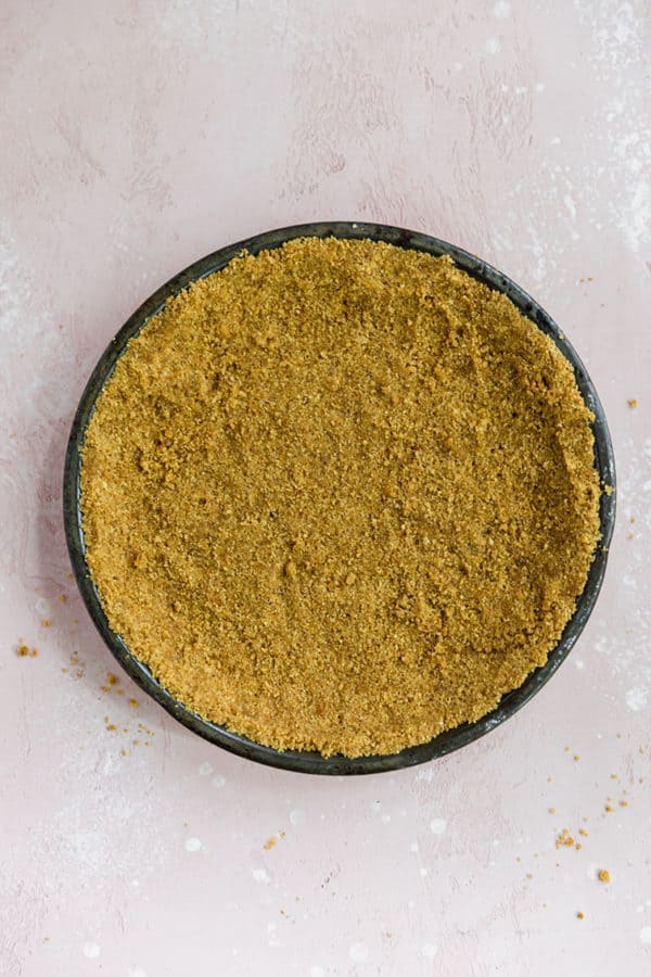 A pie plate lined with graham cracker crust.