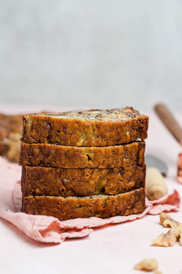A stack of banana nut bread slices on a pink tea towel.