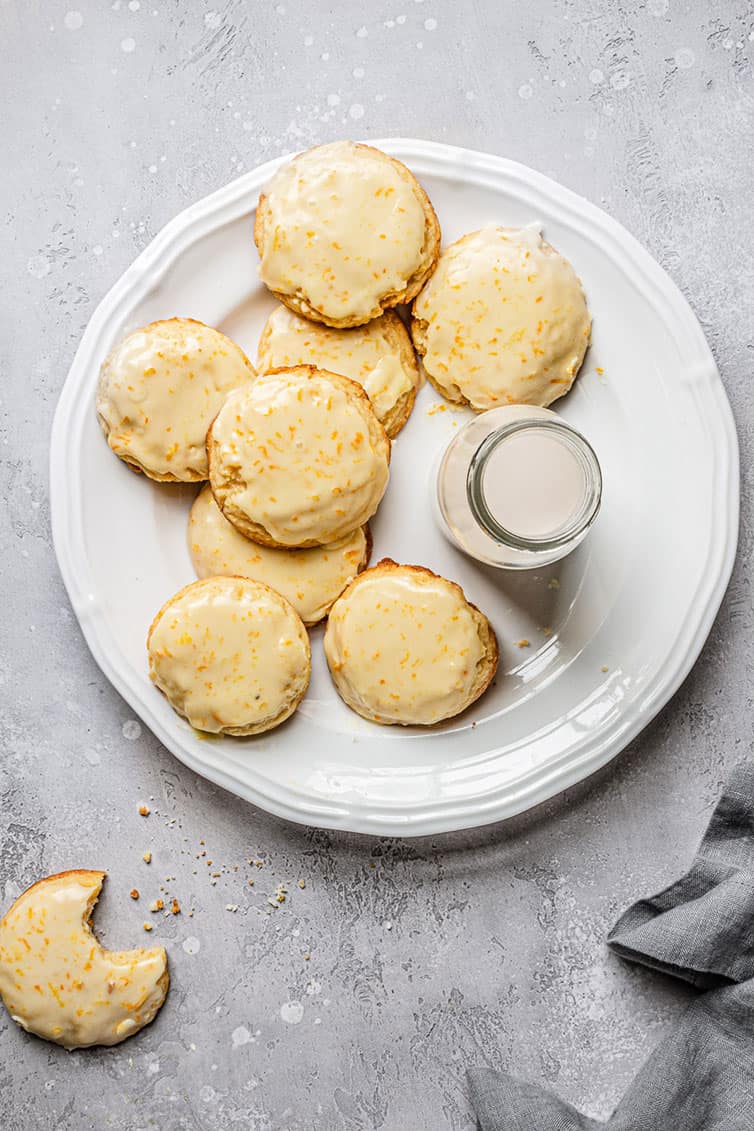 An overhead photo of orange cookies on a plate with a cut of milk.