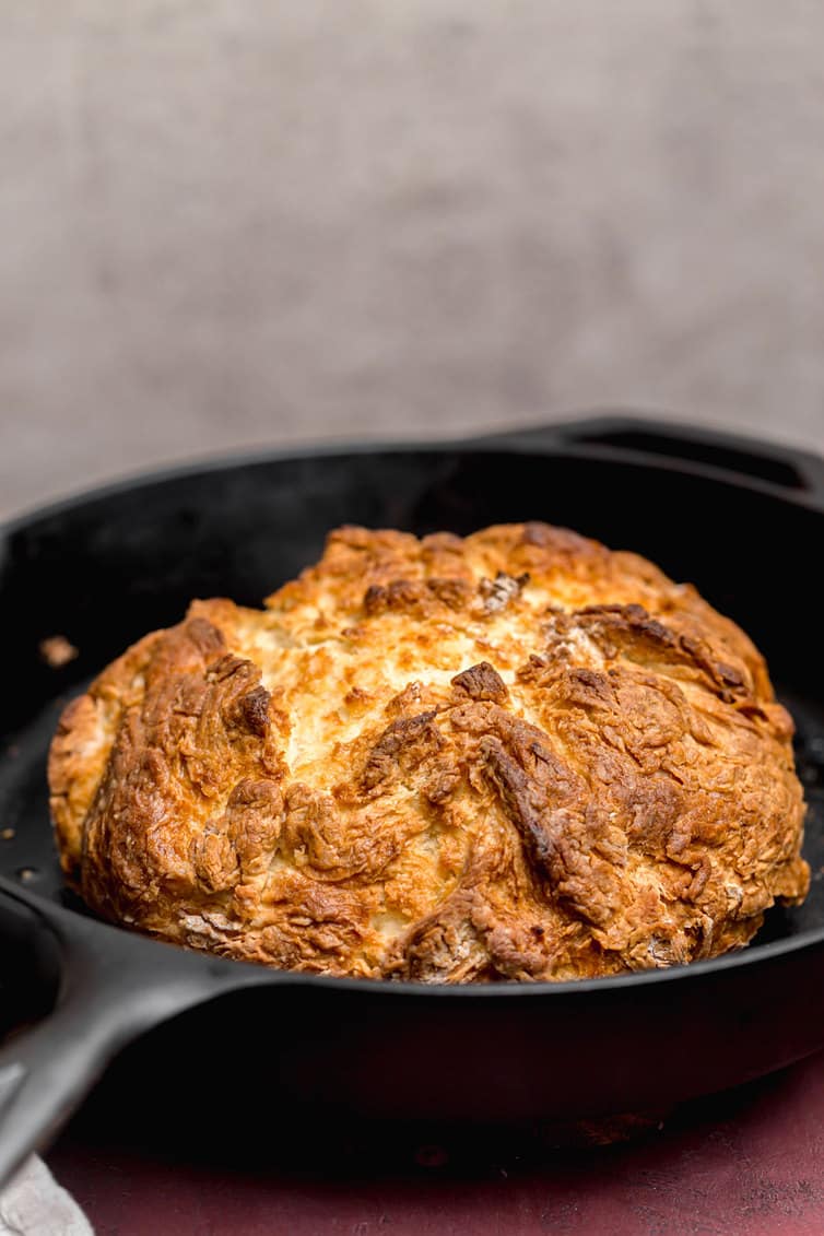 A loaf of baked Irish soda bread in a cast iron skillet.