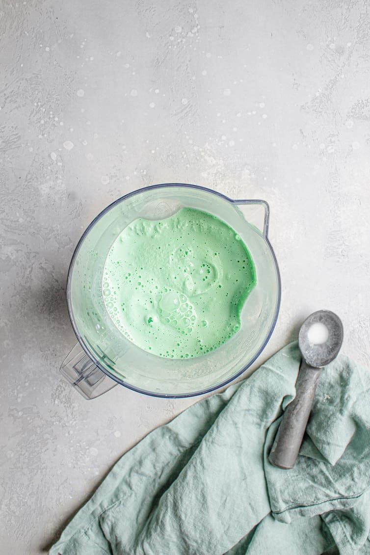 A blender with homemade McDonald's shamrock shake.