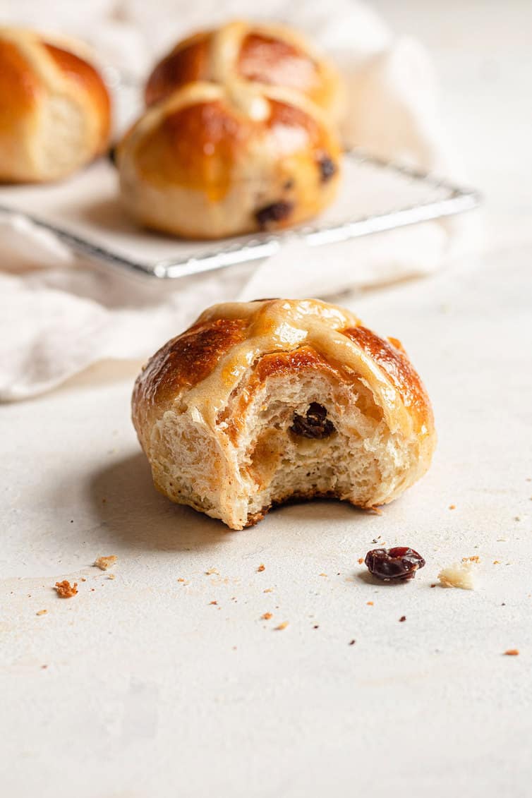 Hot cross bun with bite taken out and others in the background.