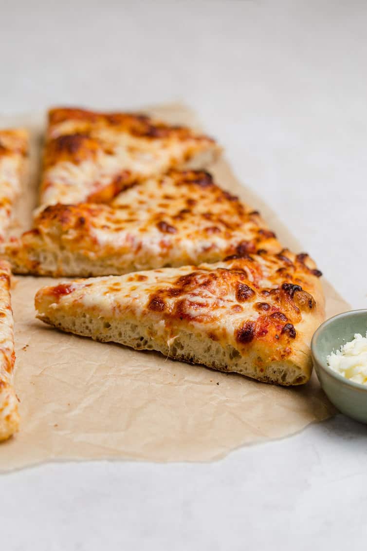 Sliced piece of pizza on parchment paper.