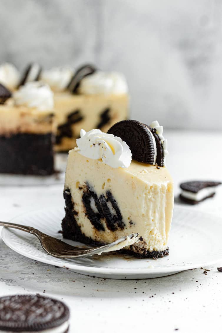 A slice of Oreo cheesecake on white plate with fork.