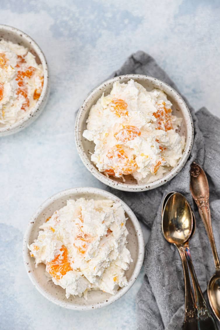 Two individual bowls of ambrosia with spoons.