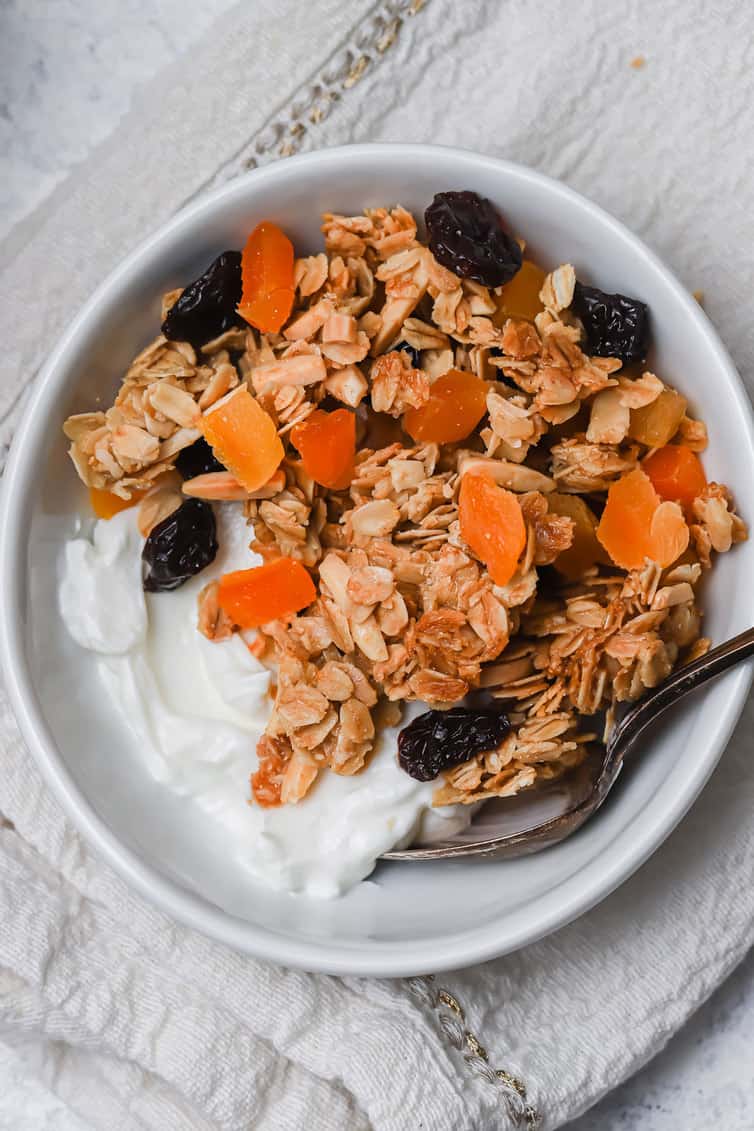 A bowl of yogurt topped with granola and dried fruit.
