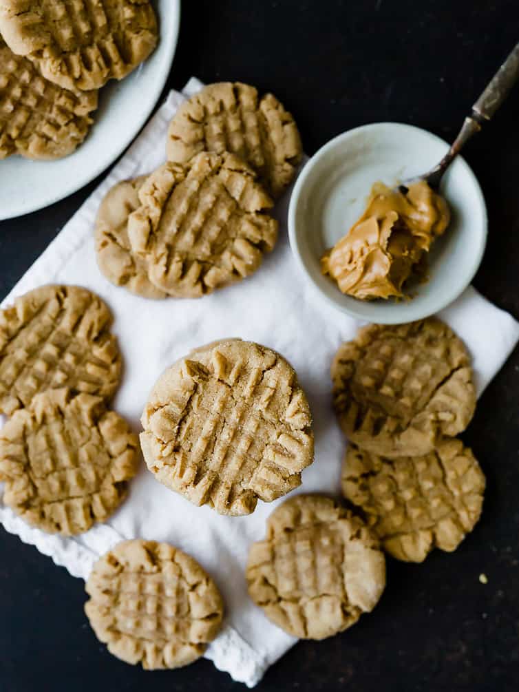 An overhead photo of baked peanut butter cookies with a spoonful of peanut butter.