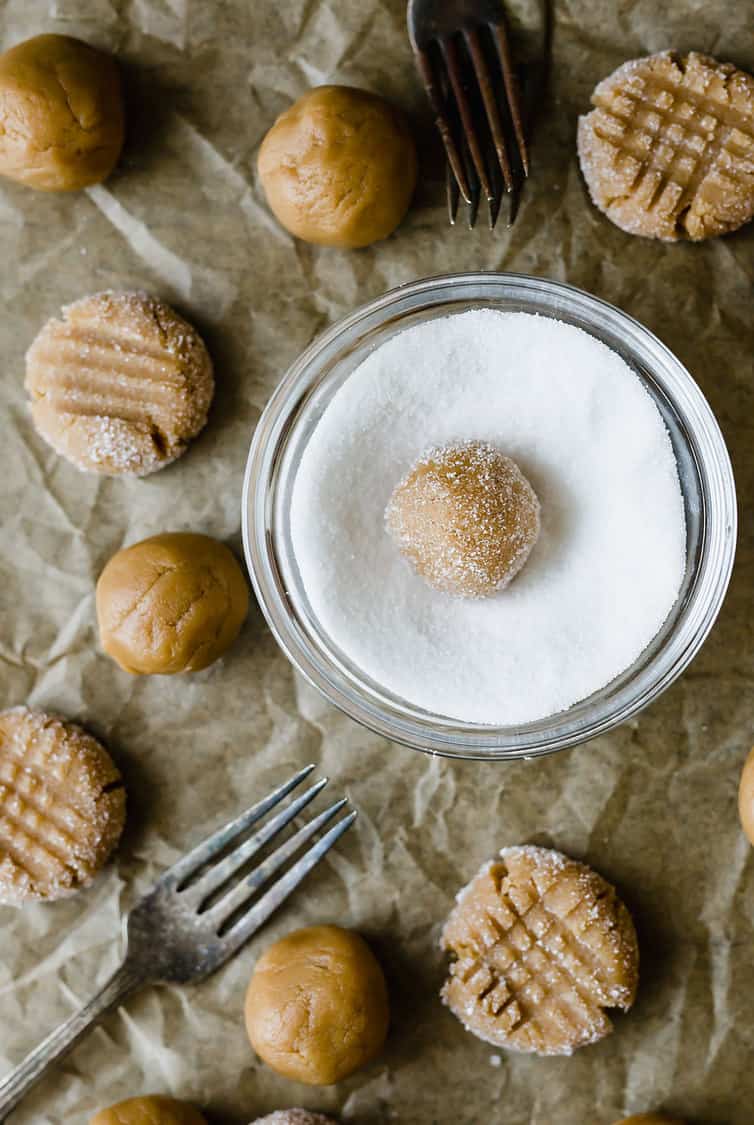 Peanut butter cookie dough balls rolled in a bowl of sugar.