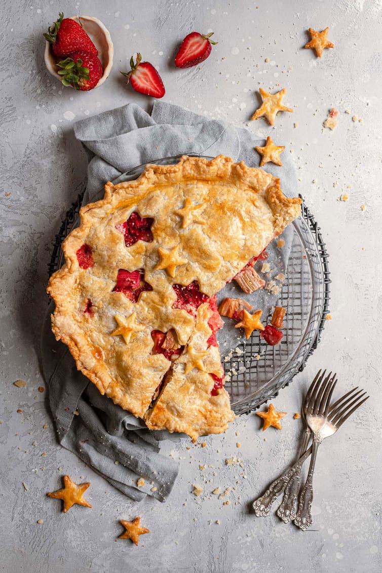 Overhead photo of strawberry rhubarb pie with two slices missing.