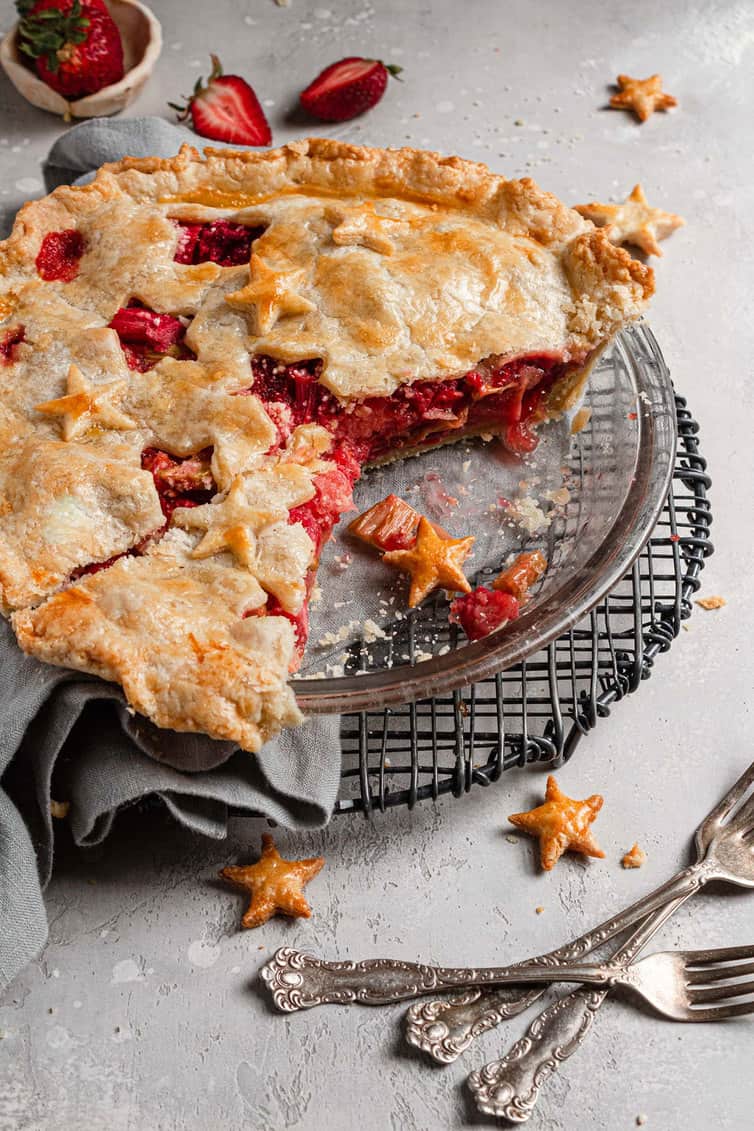 Strawberry rhubarb pie in pie plate with two slices missing.