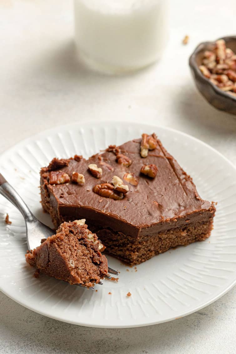 Slice of Texas sheet cake on a white plate with a forkful taken out.
