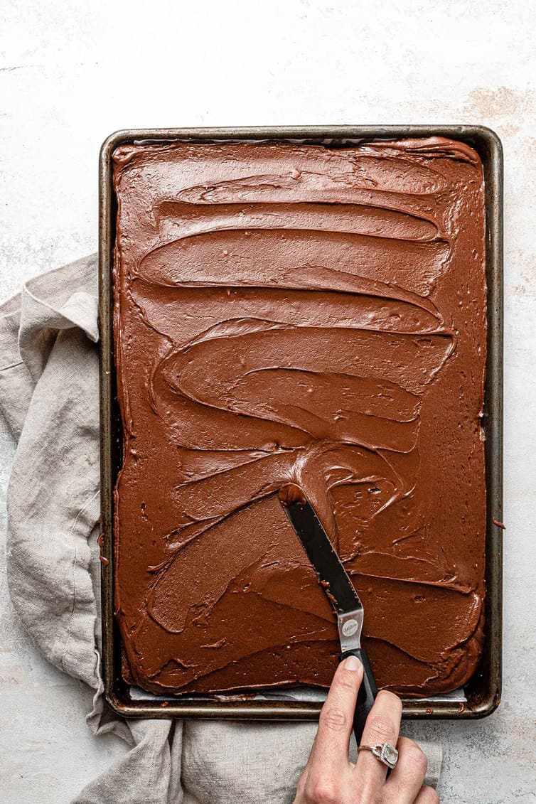 Spreading chocolate frosting on Texas sheet cake.
