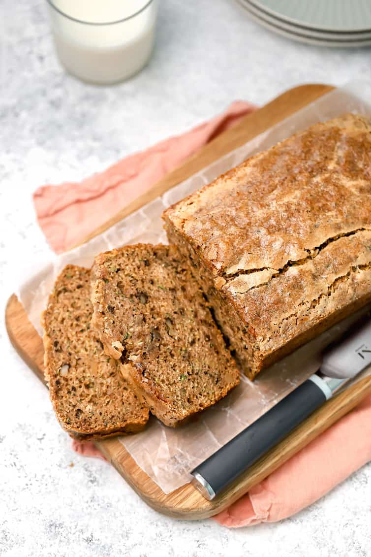 Overhead photo of zucchini bread on cutting board with two pieces sliced off.